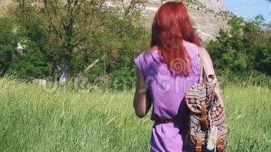 那个穿着淡紫色连衣裙的红发女孩，背着一个背包和一袋<strong>草药</strong>穿过一片<strong>草甸</strong>。